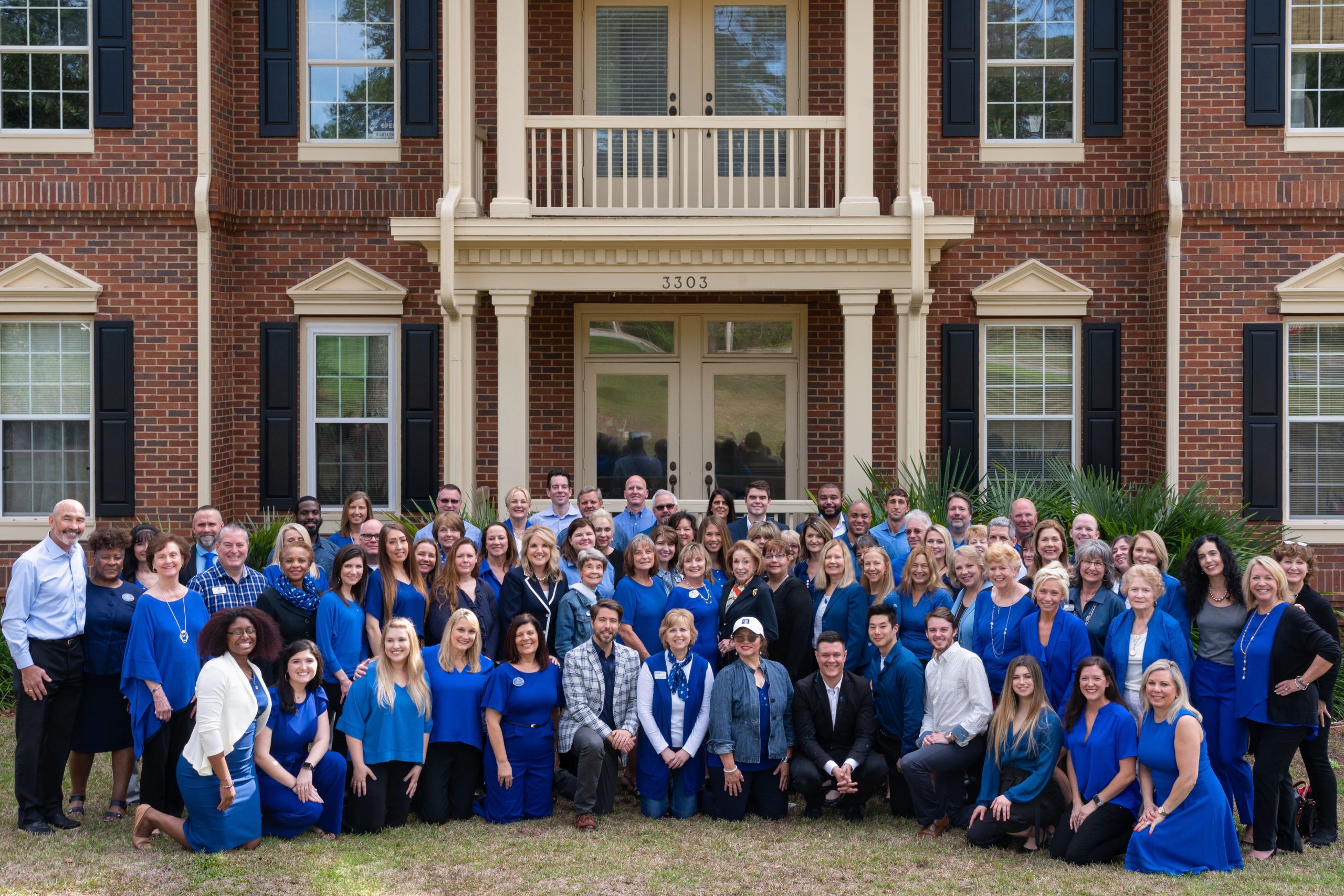 Coldwell Banker Hartung realtors, posing outside the office building, all wearing blue.