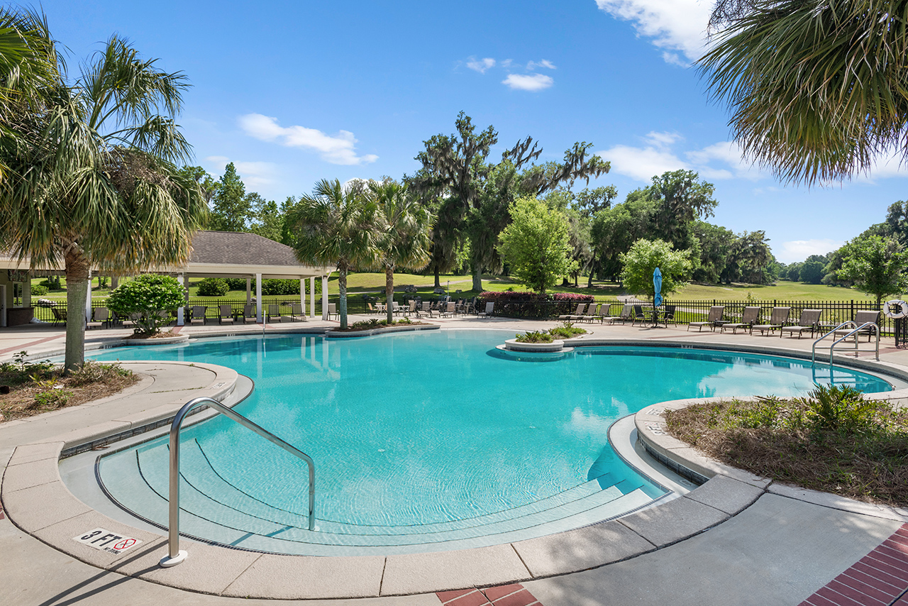 Country club pool with palm trees and golf course in background